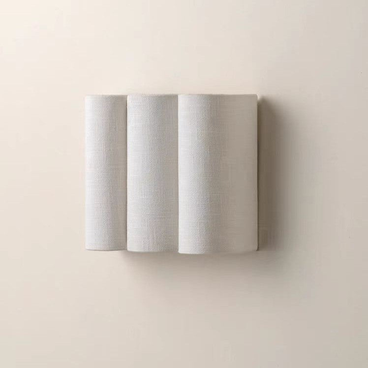 Vague fabric wave headboard sconce above a bed